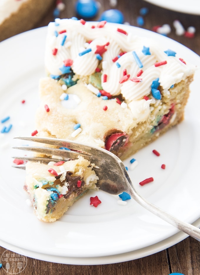 A fork cutting into a slice of a red white and blue giant sugar cookie cake.