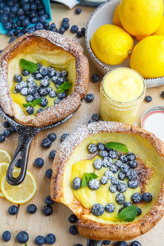 Two small dutch babies in pans filled with lemon curd and blueberries. 