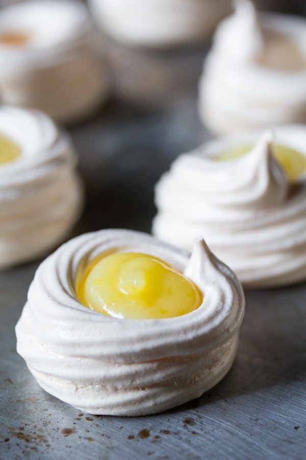 Rounded meringue cookies filled with lemon curd in the middle of them. 