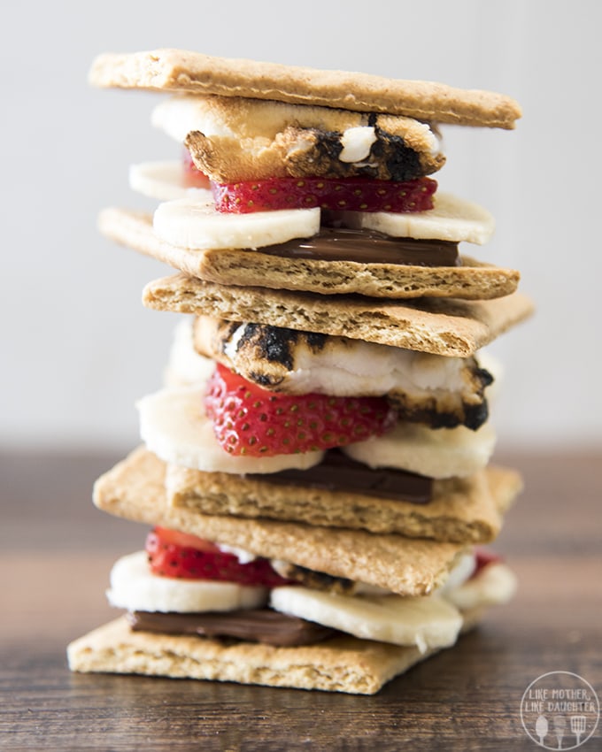A stack of graham cracker s\'mores filled with banana slices and strawberry slices. 