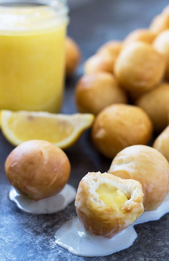 Donut holes filled with lemon curd, one is open showing the middle. 