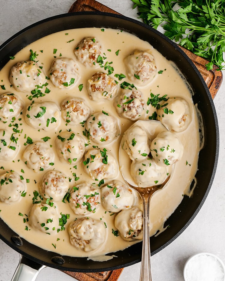 Swedish meatballs in a pot, in a creamy white gravy sauce, and sprinkled with fresh parsley.