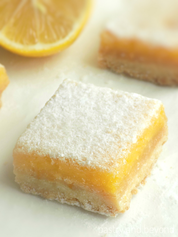 A square lemon bar topped with powdered sugar.