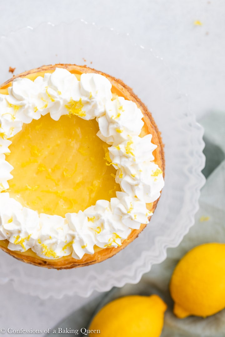 An overhead photo of a cheesecake topped with yellow lemon curd and a ring of whipped cream on the edges.