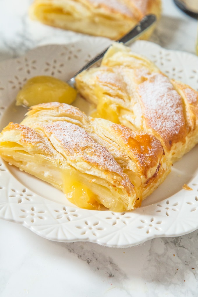 Two pieces of a lemon braided pastry on a plate. 