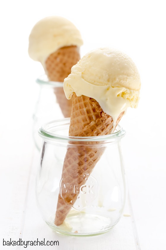 An ice cream cone with lemon ice cream on top, sitting in a glass jar. 