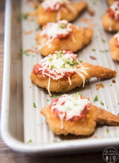 Breaded shrimp topped with tomatoes, and cheese, with fresh parsley on top.