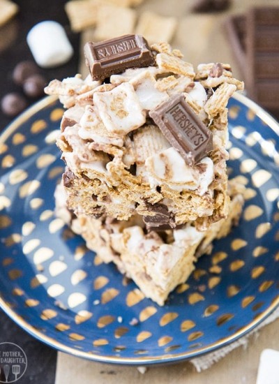 Two smores rice krispy treats on a plate with hersheys chocolate pieces.