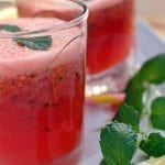 A glass of a watermelon drink topped with mint.