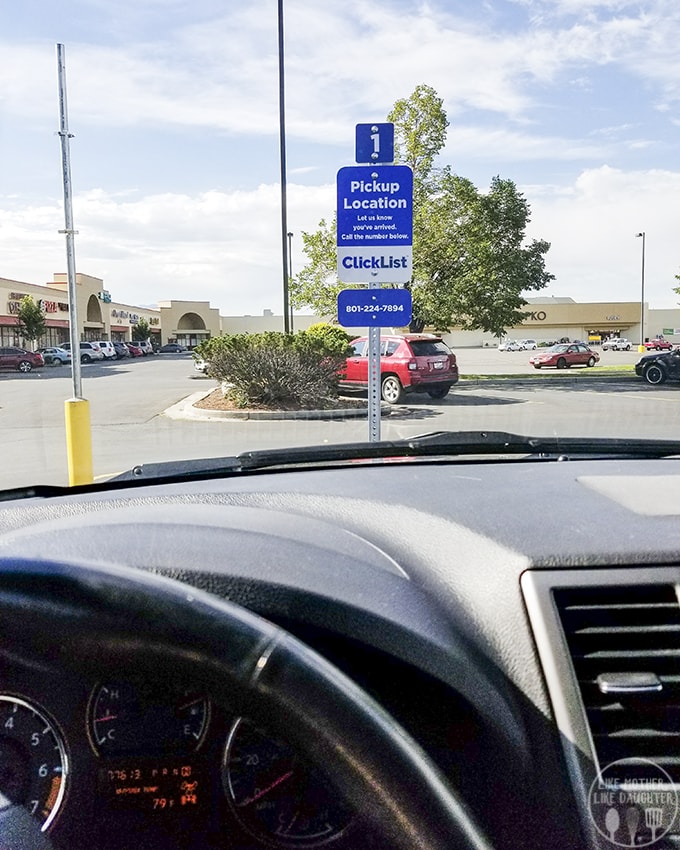 A car parked in a parking lot, showing a sign for their curbside delivery. 