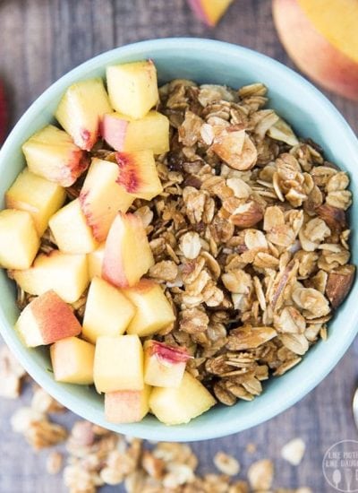 An overhead photo of coconut and almond granola topped with diced peaches.