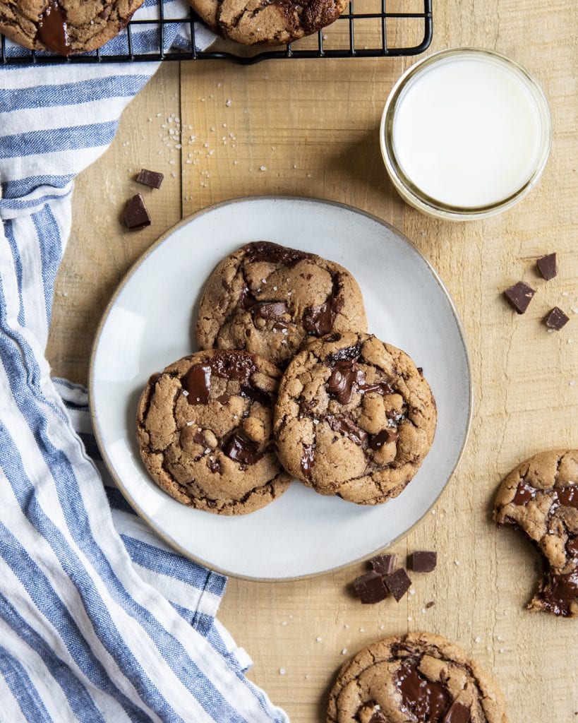 An overhead photo of a plate of three nutella chocolate chip cookies and a glass of milk.