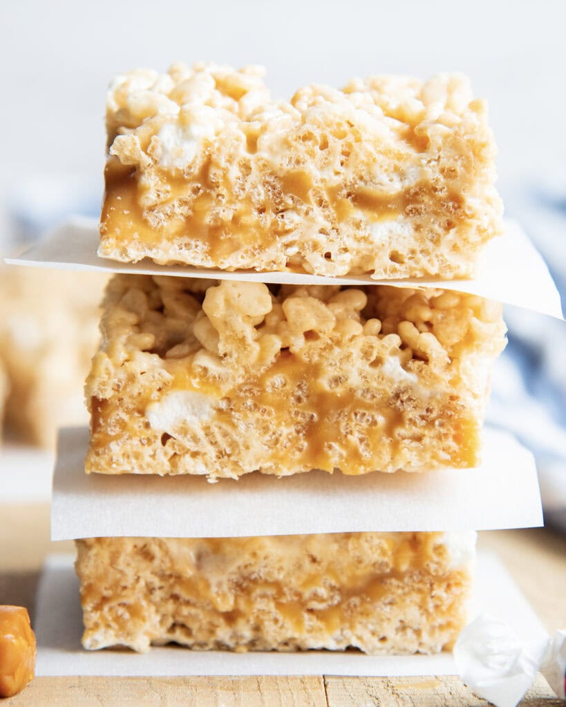 A stack of three rice krispie treats with a caramel layer in the middle of them.