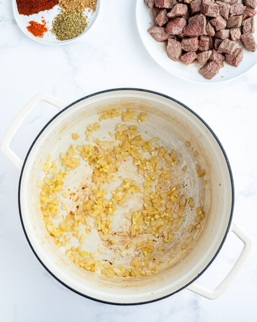 Sauteed onion pieces in a large pot.
