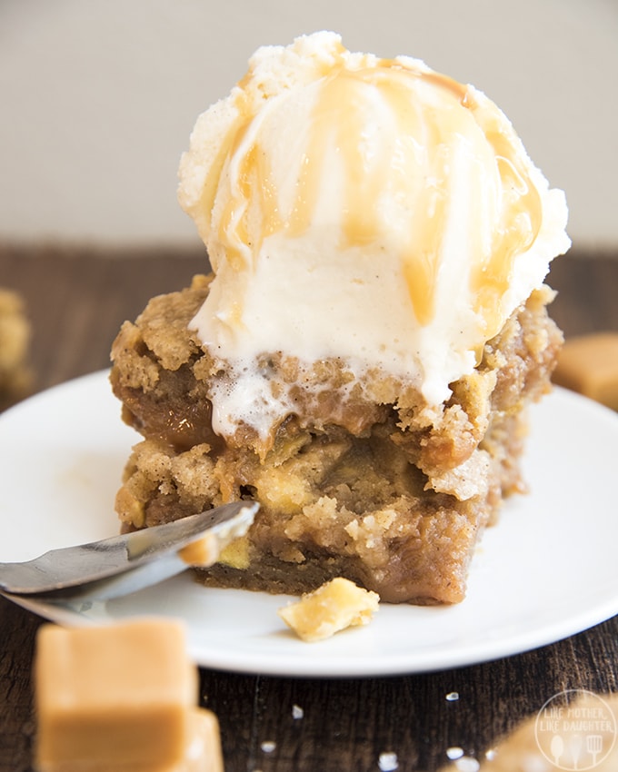 A stack of caramel apple blondies topped with vanilla ice cream.