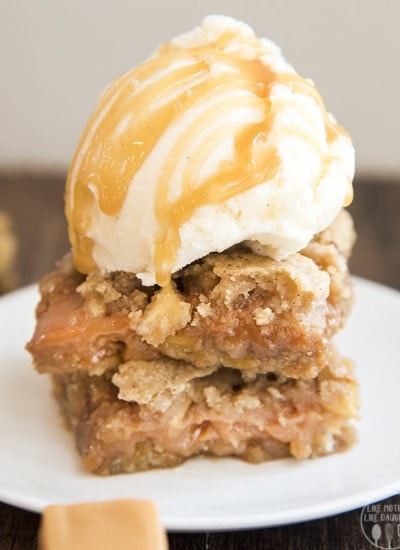 Two caramel apple blondies on a plate with a scoop of ice cream on top.