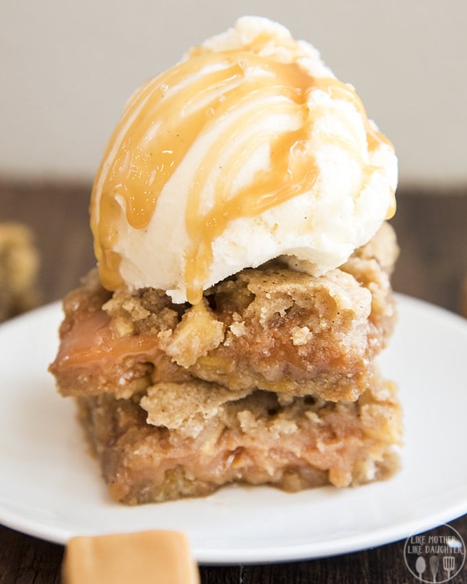 Two caramel apple blondies on a plate with a scoop of ice cream on top.