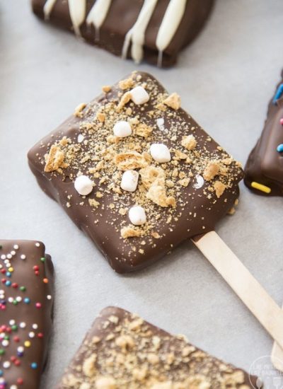A chocolate covered smores pop on parchment paper.
