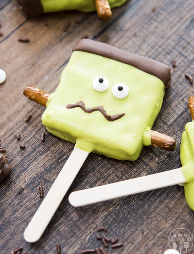 A smores pop decorated with green candy melts and eye balls to look like frankensteins monster.
