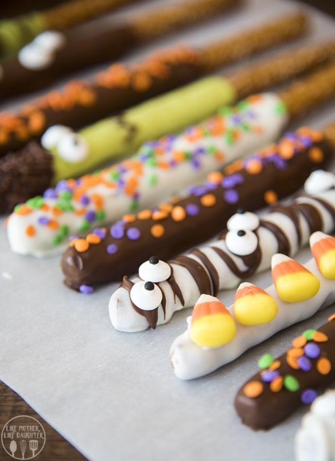 A row of Halloween decorated pretzels with sprinkles, googly eyes and candy corn.