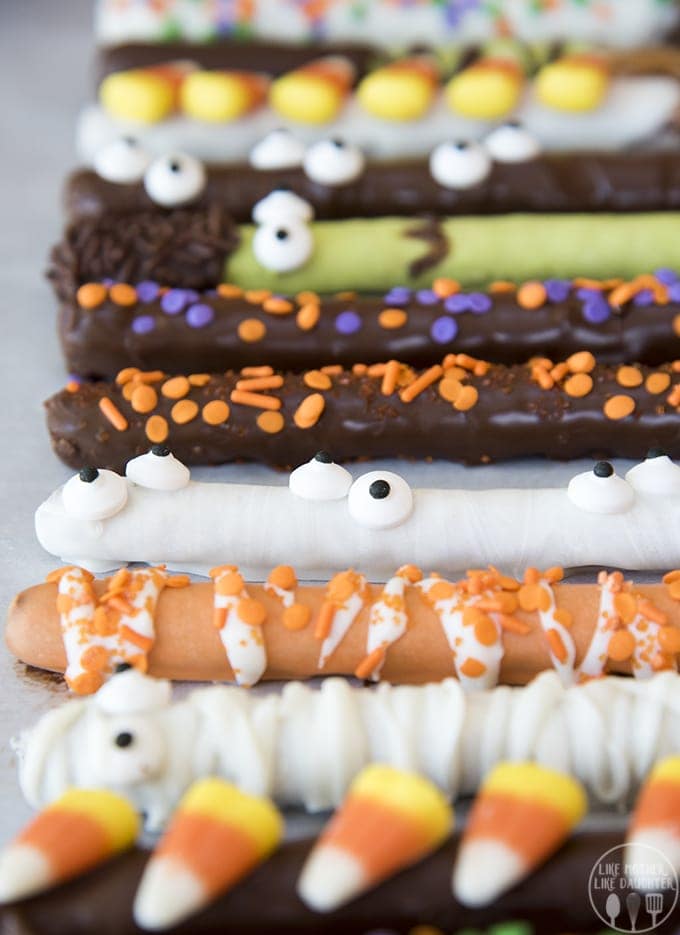 Rows of Halloween covered pretzel rods decorated with white chocolate and milk chocolate.