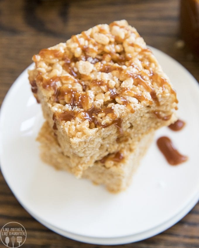 Two caramel rice krispy treats in a stack with salted caramel sauce over the top.