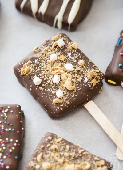 A chocolate covered smores pop on parchment paper.