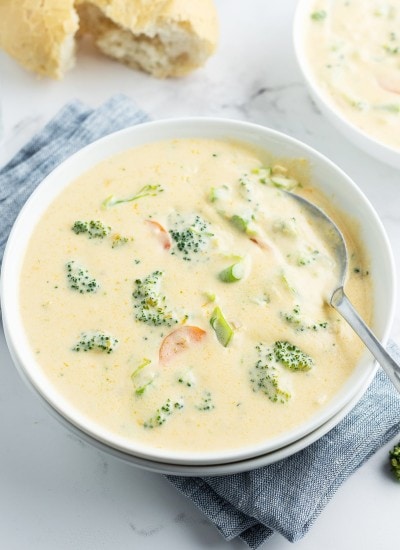 A bowl of broccoli cheese soup, with pieces of broccoli peeking out of the cheesy, creamy, soup.