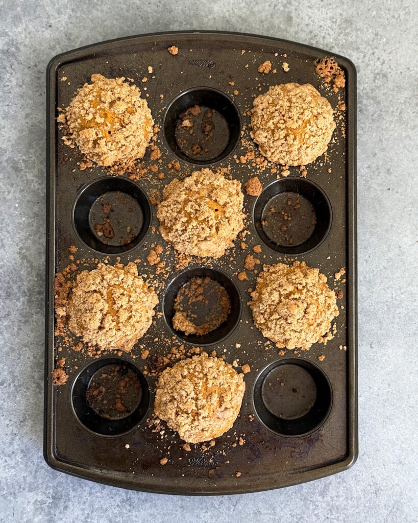 Pumpkin muffins with a crumb topping in a black muffin pan.
