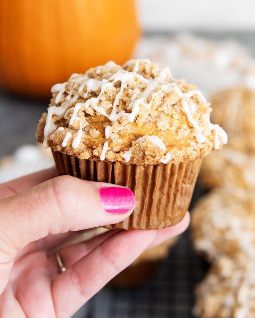 A hand holding a pumpkin streusel muffin.