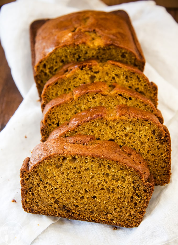 Slices of pumpkin bread laid on one another on a white cloth. 