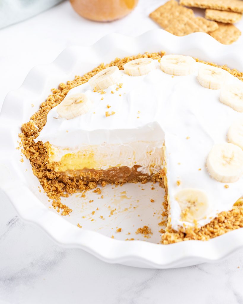 A caramel banana cream pie that is cut into in the pie plate.