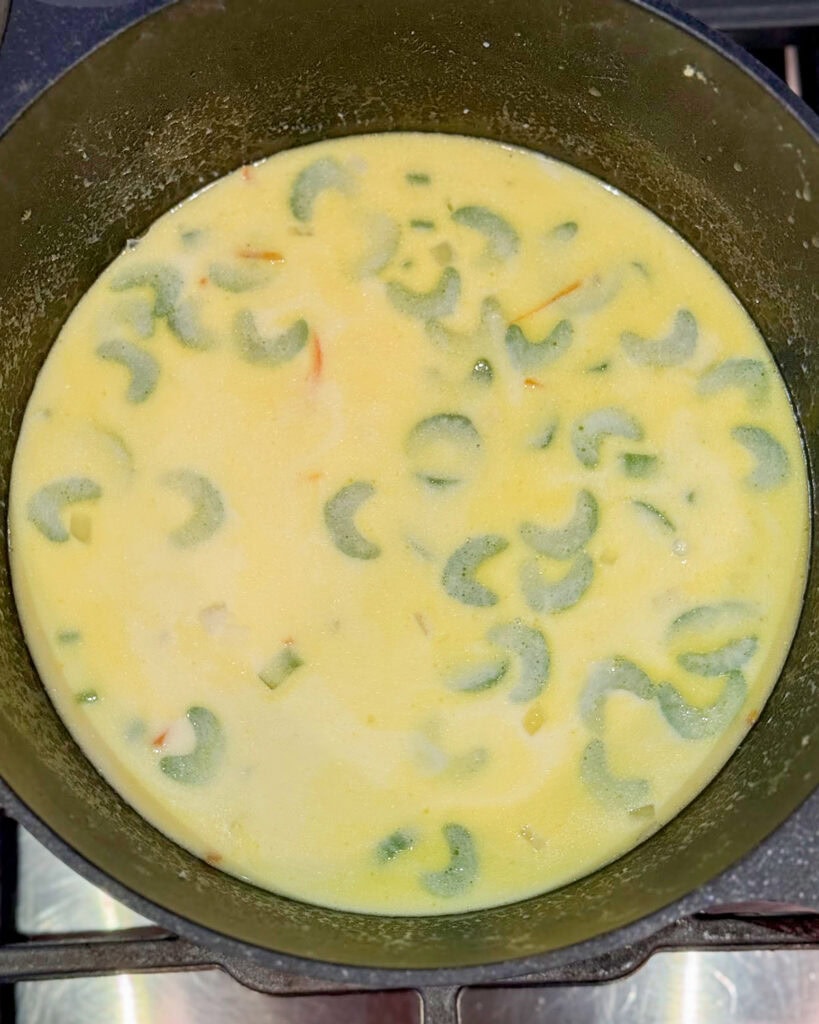 A bowl of brothy soup with celery pieces in it.