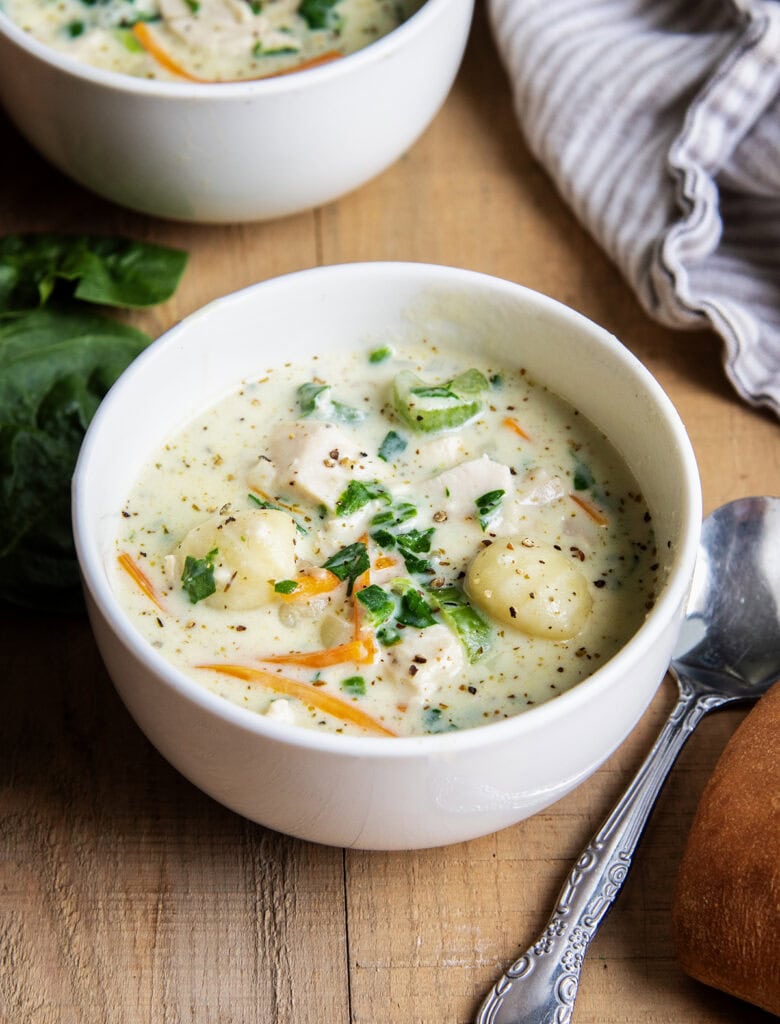 A bowl of creamy chicken gnocchi soup with carrots and celery. 