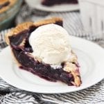 A piece of blueberry pie with ice cream on top.