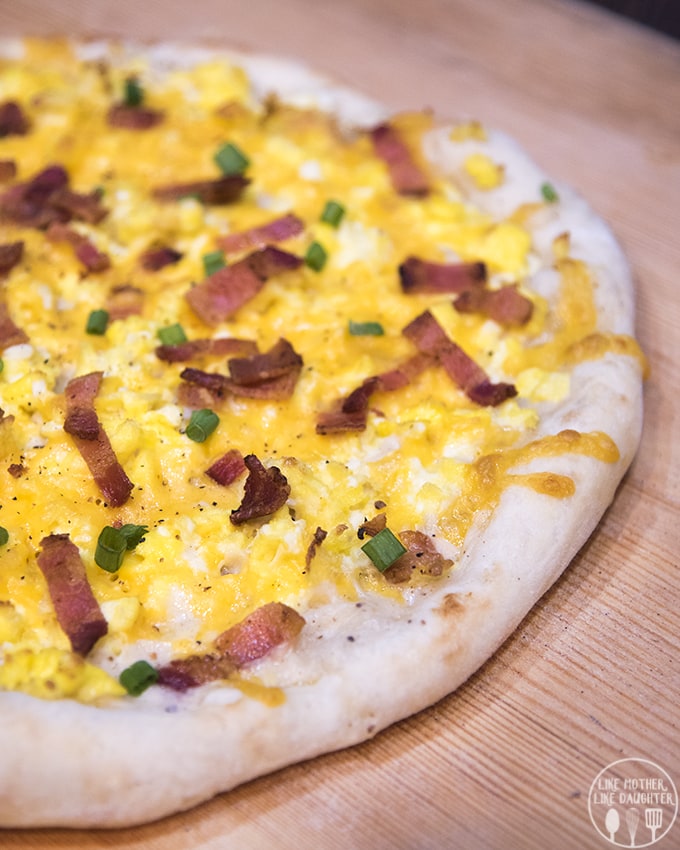 A breakfast pizza topped with cheese and sliced bacon.
