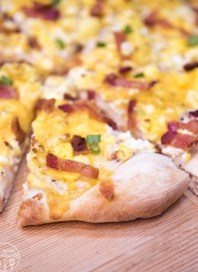 A slice of breakfast pie topped with cheese, bacon, and green onion.