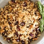 A bowl of rice pilaf with cranberries and pecans.