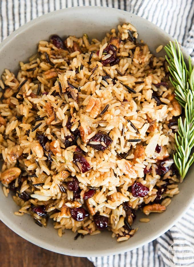 A bowl of rice pilaf with cranberries and pecans. 