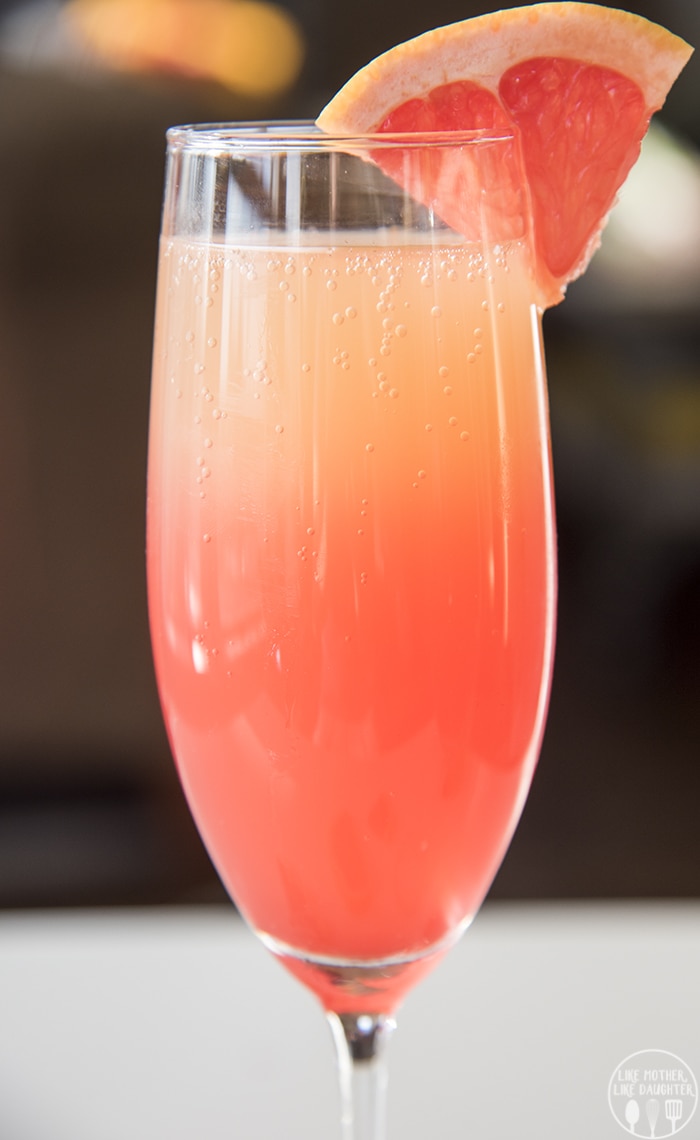 A champagne flute full of a pink and orange grapefruit drink. 