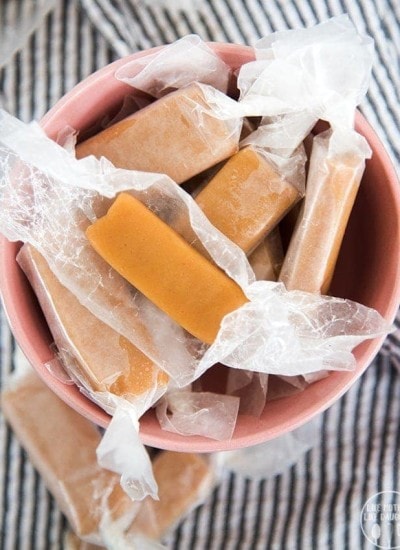 A bowl of homemade microwave caramels wrapped in waxed paper.