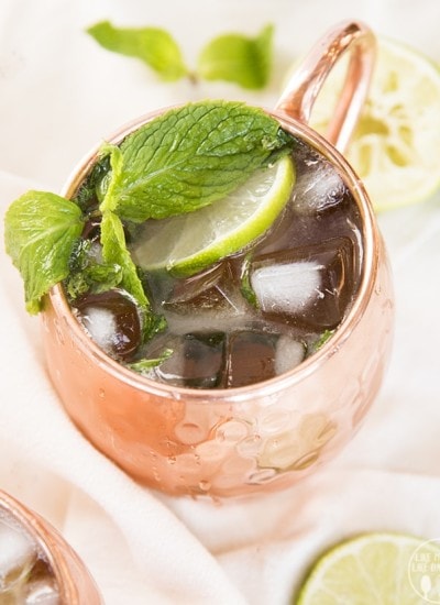 A copper mug full of ice, a lime slice, and fresh mint leaves.
