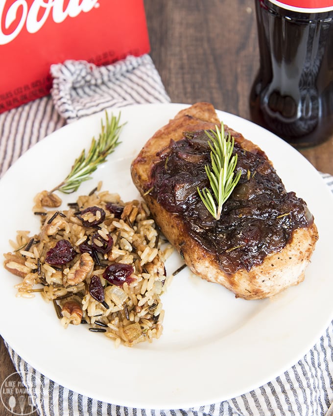 A plate with a pork chop topped with balsamic cranberry sauce, and a serving of rice pilaf. 