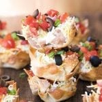A stack of three 7 layer dip wonton cups.