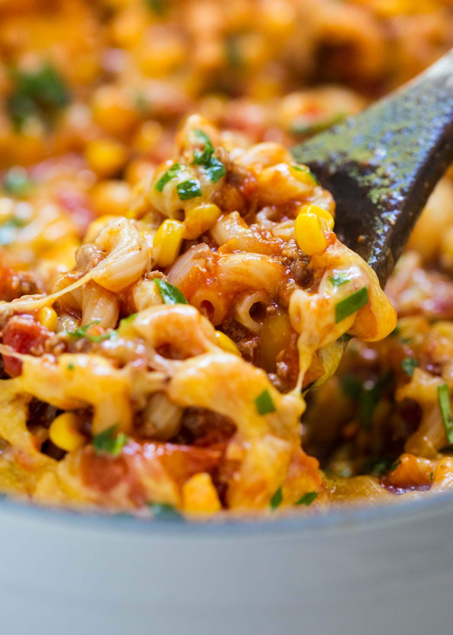 A pot of American goulash with corn and ground beef and macaroni noodles topped with cheese. 
