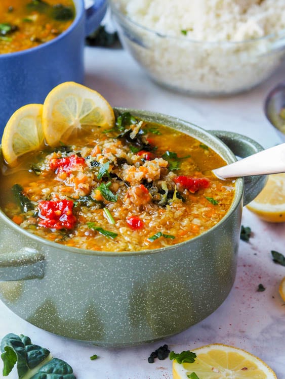 A pot of soup with lentils, quinoa, and red peppers. 