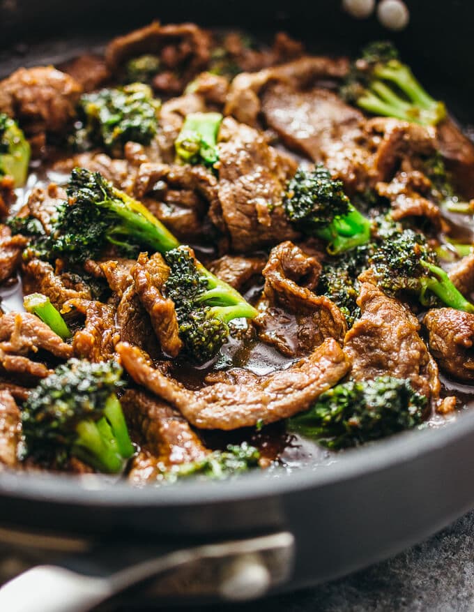A skillet full of beef strips and broccoli. 