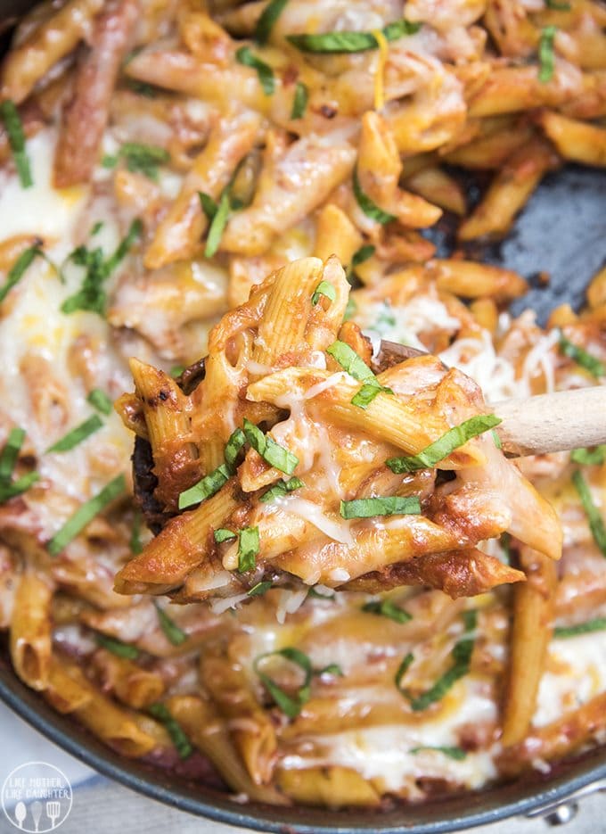A pot of penne pasta topped with cheese and basil. 