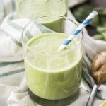A green peanut butter and banana smoothie in a glass.