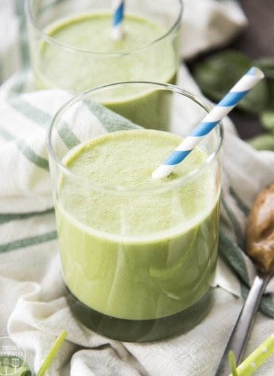 A green peanut butter and banana smoothie in a glass.